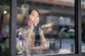 Fototapeta na wymiar Woman talk to cellphone and sit inside cafe