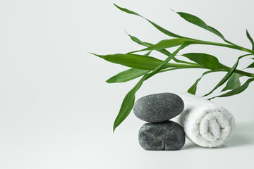 Fototapeta na wymiar Light gray background with stones, towel and bamboo.