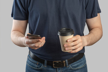Smartphone in male hands close-upA European man with a phone and coffee in his hands on a gray isolated background