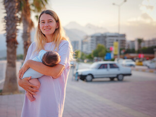 Diverse people portrait of mother with swarthy infant. mother and son on promenade in Antalya, Konyaalti beach, at summer sunset. Lovely warm family lifestyle concept.