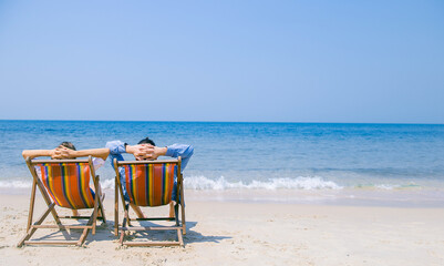 Happy retired couple enjoy beautiful sunset at the beach. Couple relax on the beach enjoying beautiful sea on the tropical island. Summer beach vacation concept