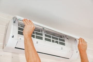 A man replaces and cleans the air cleaner filter from the air conditioner.