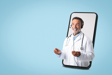 Positive european senior doctor in white coat with stethoscope, headphones on big screen phone