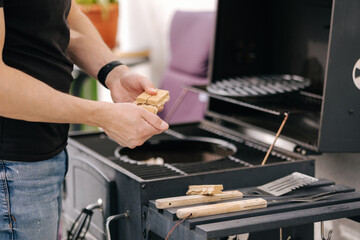 Close-up of man use fire briquettes for lighting a fire in the grill. Outdoor barbecue on terrace