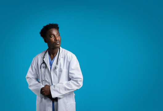 Attractive african american doctor looking at copy space, blue background