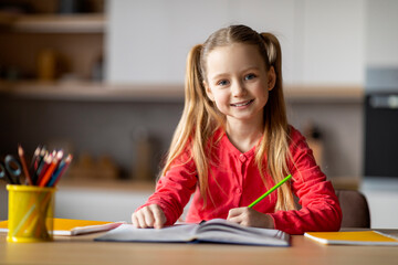 Cute Little Girl Making School Homework While Sitting At Desk At Home