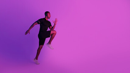 Fototapeta na wymiar Sporty African American Guy Exercising Wearing Headphones Over Purple Background