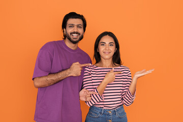 Loving young indian couple pointing at free space