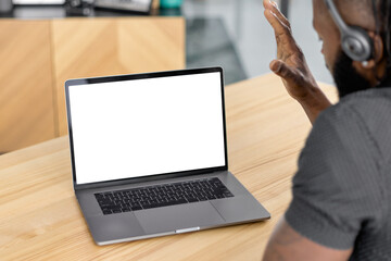 Copy space, mock-up for your design or text. Man entrepreneur, freelancer or office worker in headset with laptop with blank screen shows a greeting gesture