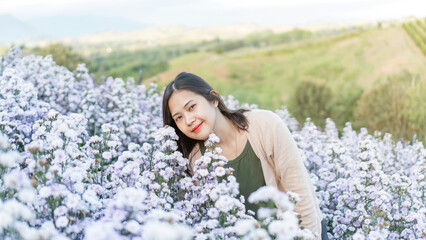 Asian woman stands among a violet margaret flower. - 600114318