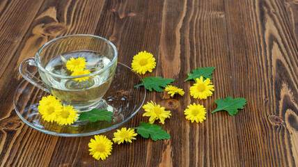 Naklejka na ściany i meble Yellow chrysanthemum flower tea on a wooden table.
