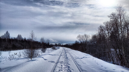 Railway in snow. Winter landscape with empty rail tracks in a cold day