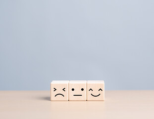 Wooden cube with happy normal and sad face icons for experience survey services and products review...