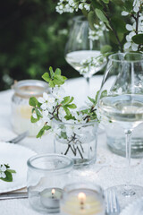 Rustic zero waste wedding decor with natural elements. Fresh spring blooming flowers, candles, linen napkins, wine glasses. Eco friendly decoration for the special holiday dinner. Romantic cozy place