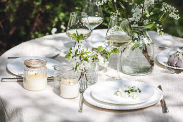 Romantic elegant luxury wedding table decor with white fresh spring blooming cherry apple tree flowers. Glass, candles, floral decoration for special marriage holiday event. No plastic zero waste