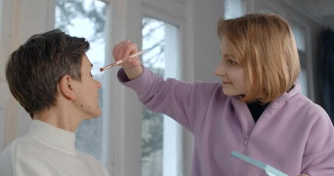 Teenage daughter makes makeup for her middle aged mom, 4k