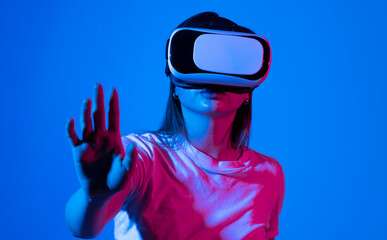 Brunette woman with VR headset touching something what she see in virtual world. Futuristic technology.