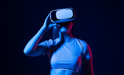 Woman using VR virtual reality glasses headset pointing at objects in metaverse. Virtual reality...