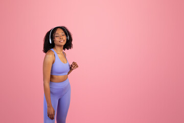 Obraz premium Smiling millennial african american lady in sportswear, wireless headphones with closed eyes enjoys music