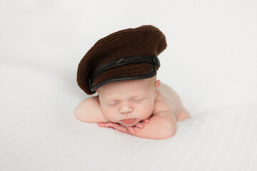 Newborn baby in cap sleeps on the handles. Newborn baby sleeps sweetly on white blanket. 