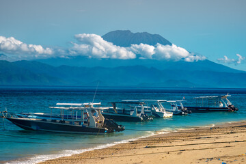 Fototapeta na wymiar Passenger boats in Nusa Penida with the iconic Mount Agung (Gunung Agung) volcano on mainland Bali in the background, Indonesia