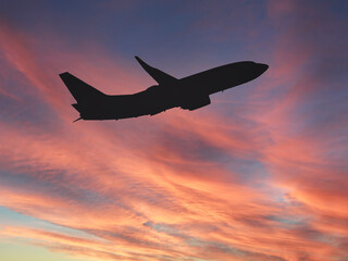 Silhouette of a commercial aircraft against a sunset sky. Travel concept.