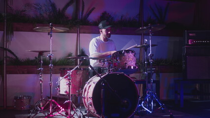 A professional male artist plays a drum kit. Night show in a musical instrument recording studio....