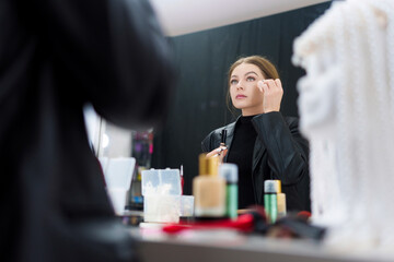 Woman applying base make-up on her face backstage