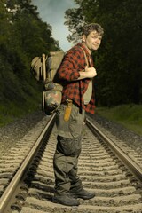 Adventurer with retro haversack wandering nature on railroad way