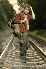 Adventurer with retro haversack wandering nature on railroad way - obrazy, fototapety, plakaty