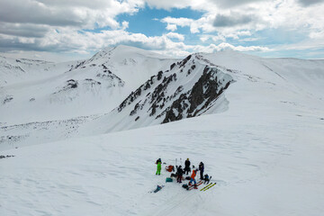 A group of people on skis stand on a snowy mountain.
