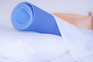 Yoga mat lies in bed on a pillow under a blanket, yoga concept