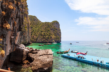 Fototapeta na wymiar Pier or jetty on phi phi leh island in krabi in thailand near maya bay with boats and tourists on a hot sunny day. Travel and vacation.