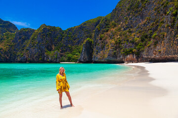Beautiful young blonde woman in orange dress on a Maya Bay Beach during excursion of phi phi leh...