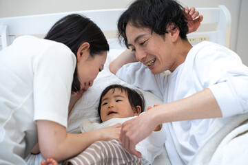 Fototapeta na wymiar ベッドで子供の面倒を見る日本人の親子