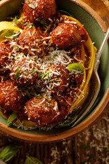 Meatballs in a tomato sauce with Pappardelle pasta sprinkled with parmesan cheese and chopped fresh basil, close up view