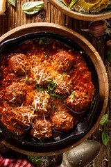 Meatballs with tomato sauce, sprinkled with parmesan cheese and fresh chopped basil, close up view.