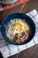 a blue bowl of gyudon ramen with egg and onion leeks