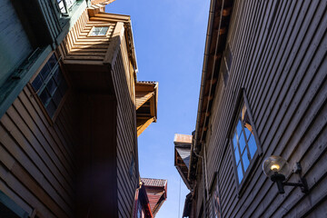 Blue sky in a narrow wooden street with roofs and interesting houses