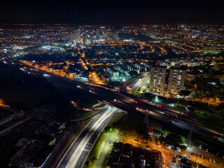 Fototapeta na wymiar Night aerial photography of the city of Campinas, São Paulo. Dramatic shadows, dark skies and just lights from cars and surrounding buildings. Shopping Unimart and Anhanguera Highway.
