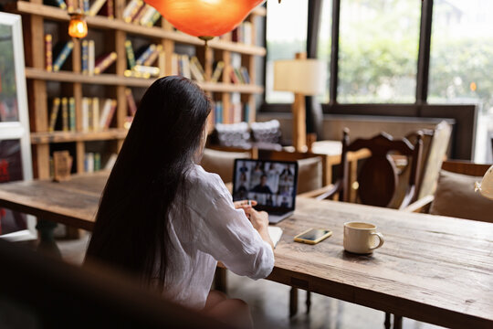 Young Caucasian business woman with long brunette hair working on laptop in cafe. College student using technology , online education, freelance