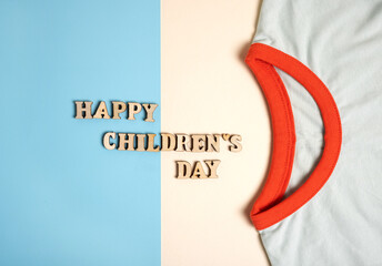 happy childrens day inscription formed from wooden letters.happy has shape of smile.t shirt sleeves...