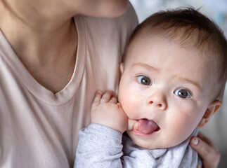 cute baby boy is lying on bed or sitting in mother arms,beautiful child big eyes.mommy woman...