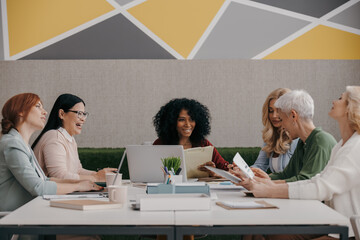 Fototapeta premium Group of mature women discussing business while having meeting in the office