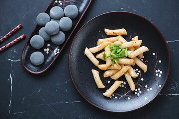 Korean traditional rice cakes tteokbokki and mochi on a black marble background, horizontal shot,...