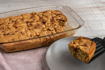 Pieces of cut apple pie from a bowl are laid out on a plate. Close-up of a woman's hand with a spatula takes out pieces of cut fruit pie and puts it on a plate. Homemade pastries for a sweet dessert