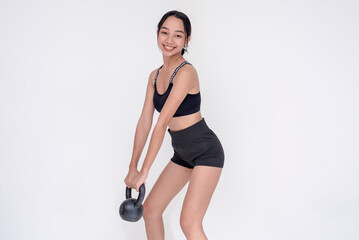Fototapeta na wymiar A happy and fit young woman weightlifting by holding a kettle bell, side view. Isolated on a white background.