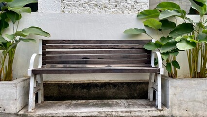 One old rustic bench, made of wood, grey color with house plant on the left and right side, white...