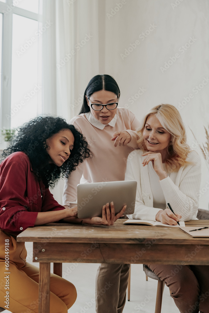 Canvas Prints three confident mature women using digital tablet while working in office together