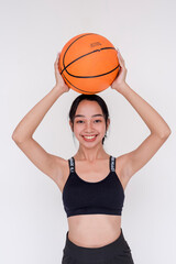 A sporty and athletic young woman posing while holding up a basketball above the head with both hands. Isolated on a white background.